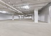 Thumbnail 18 of 18 - A long hallway with white pillars and pipes on the ceiling.