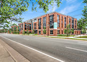 Thumbnail 10 of 18 - A street view of a red brick building with a clear blue sky above.
