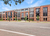 Thumbnail 9 of 18 - A row of red brick apartment buildings with trees in front.