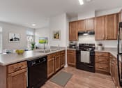 Thumbnail 3 of 18 - A kitchen with wooden cabinets and black appliances.