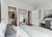 Thumbnail 5 of 18 - A bedroom with a large bed and a wardrobe with clothes hanging.