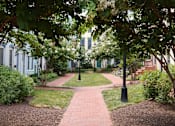 Thumbnail 3 of 4 - A pathway with a grassy area on either side and a building in the background.