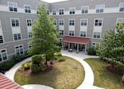 Thumbnail 2 of 4 - A courtyard with a tree and a building in the background.