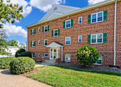 Thumbnail 1 of 18 - A red brick building with green shutters and a white door.