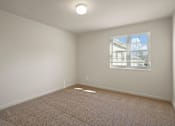 Thumbnail 17 of 18 - A room with a carpeted floor and a window showing a building outside.