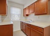 Thumbnail 8 of 18 - A kitchen with brown cabinets and a white countertop.