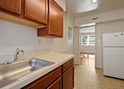 Thumbnail 9 of 18 - A kitchen with a white fridge and brown cabinets.