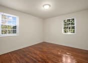 Thumbnail 14 of 18 - A room with wooden floors and two windows.