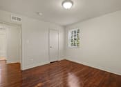 Thumbnail 12 of 18 - A room with wooden floors and a window with a view of trees.