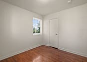 Thumbnail 13 of 18 - A room with a white door and a window with a view of trees and a house outside.