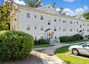 Thumbnail 2 of 18 - A white building with a car parked in front.