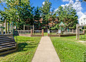 Thumbnail 5 of 18 - A park with a playground and a wooden bench.