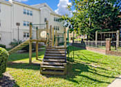 Thumbnail 7 of 18 - A playground with a slide and a green fence.
