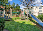 Thumbnail 6 of 18 - A playground with a slide and a green gate.