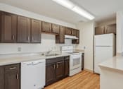 Thumbnail 2 of 20 - A kitchen with white appliances and brown cabinets.