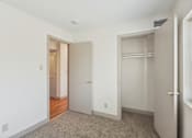 Thumbnail 12 of 20 - A white room with a carpeted floor and two doors.