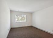 Thumbnail 8 of 20 - A room with a window and carpeted floor.