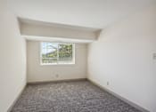 Thumbnail 10 of 20 - A room with a window and a carpeted floor.