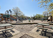 Thumbnail 16 of 20 - A playground with a slide, swings, and picnic tables.