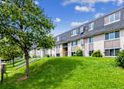 Thumbnail 1 of 30 - a building with a green lawn and a tree in front of it