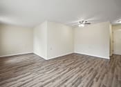Thumbnail 4 of 12 - an empty living room with wood flooring and a ceiling fan