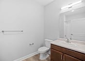 Thumbnail 23 of 31 - A white bathroom with a toilet, sink, and mirror.