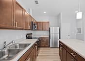 Thumbnail 20 of 31 - A kitchen with brown cabinets and a stainless steel refrigerator.
