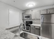 Thumbnail 2 of 35 - a kitchen with granite counter tops and stainless steel appliances at Midtown Crossing in Raleigh, North Carolina 27609