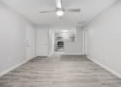 Thumbnail 7 of 35 - an empty living room with a ceiling fan and a kitchen at Midtown Crossing in Raleigh, 27609