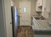 Thumbnail 32 of 45 - A kitchen with a refrigerator, cabinets, and a countertop.