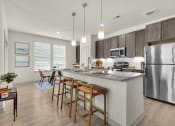 Thumbnail 1 of 35 - spacious kitchen with stainless steel appliances and a large island with stools at The Enclave at Deer Moss Creek, Niceville