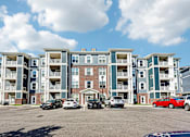 Thumbnail 51 of 51 - A large apartment complex with cars parked in front.