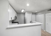 Thumbnail 34 of 67 - A kitchen with white cabinets and a white countertop.