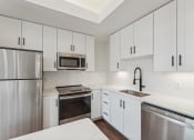 Thumbnail 2 of 46 - an empty kitchen with white cabinets and stainless steel appliances