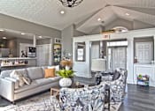 Thumbnail 10 of 21 - A living room with a grey couch and a grey and white patterned chair.