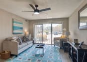 Thumbnail 21 of 52 - a living room with a couch and a desk and a ceiling fan  at Bayville Apartments, Virginia Beach, VA, 23455