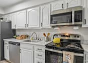 Thumbnail 28 of 54 - A kitchen with white cabinets and a black stove top.