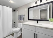 Thumbnail 22 of 67 - A white bathroom with a toilet, sink, and shower.