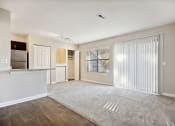 Thumbnail 9 of 33 - the living room and kitchen of an apartment with a large window and sliding glass doors
