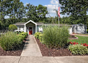 Thumbnail 11 of 14 - A small building with a red door is surrounded by a garden.