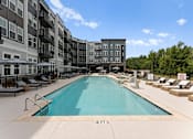 Thumbnail 16 of 25 - A large swimming pool in front of apartment buildings.