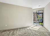 Thumbnail 40 of 64 - A room with a carpeted floor and a sliding glass door leading to a balcony.