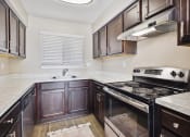 Thumbnail 2 of 33 - the kitchen of a home with dark wood cabinets and white countertops