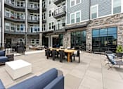 Thumbnail 19 of 25 - A patio area with a table and chairs is surrounded by apartment buildings.