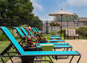 Thumbnail 13 of 21 - A row of blue and green lawn chairs are arranged in a row by a pool.