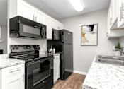 Thumbnail 1 of 46 - A kitchen with black appliances and white cabinets.