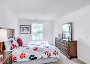 Thumbnail 5 of 17 - A bedroom with a floral bedspread and a wooden dresser.