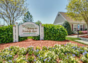 Thumbnail 17 of 17 - A sign for The Glens at Thillers Lane Apartment Homes is surrounded by flowers.