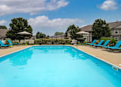 Thumbnail 14 of 21 - A large blue swimming pool with lounge chairs around it.