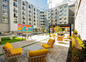 Thumbnail 8 of 36 - a courtyard with yellow chairs and tables in front of an apartment building